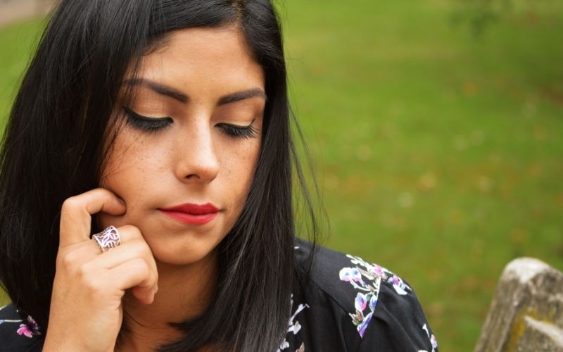 Woman dealing with betrayal trauma and in distress, holding her phone.